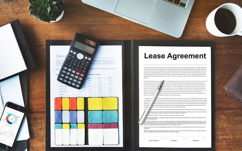 lease agreement on the table with calculation and other things on the side